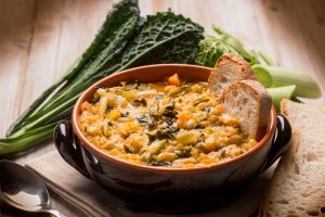 Ribollita Tuscan bread and vegetable soup with white beans and kale, served in traditional terrocotta bowl.